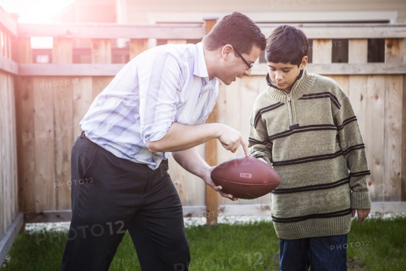 Hispanic father teaching son to play football