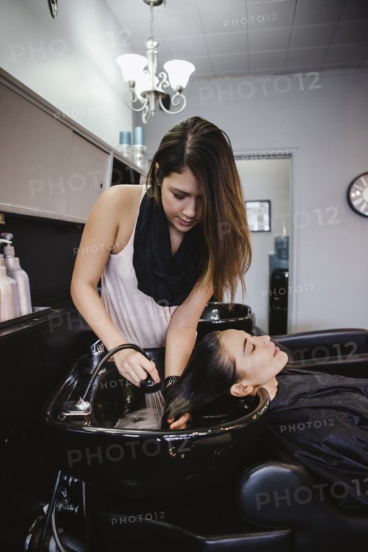 Stylist washing client's hair in salon
