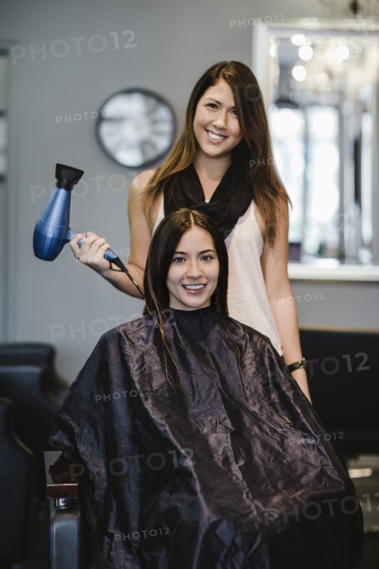 Stylist blow drying client's hair in salon