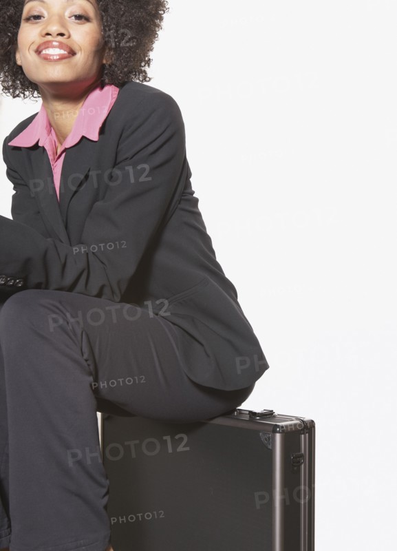 Businesswoman sitting on metal briefcase