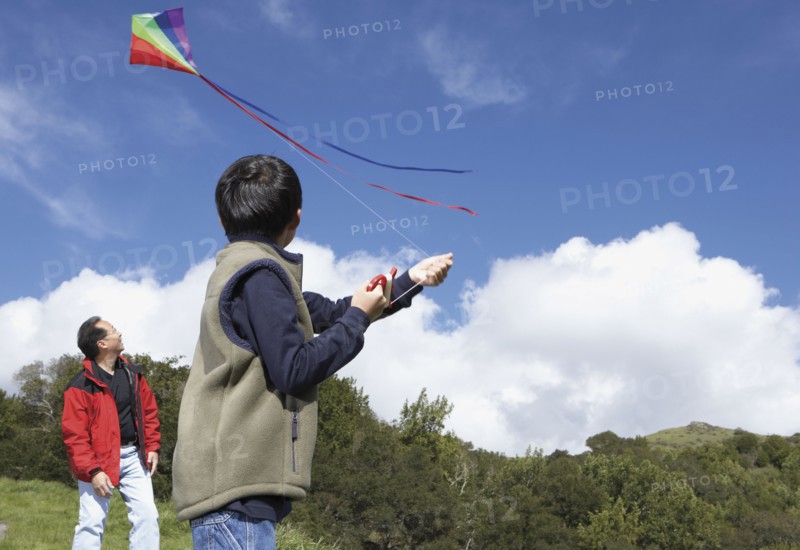 Asian father and son flying a kite