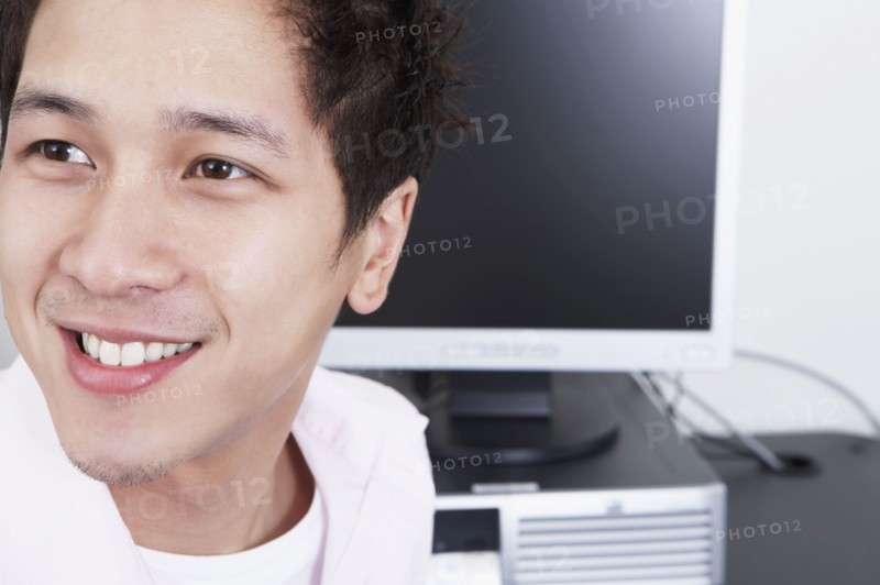 Close up of young Asian man next to computer