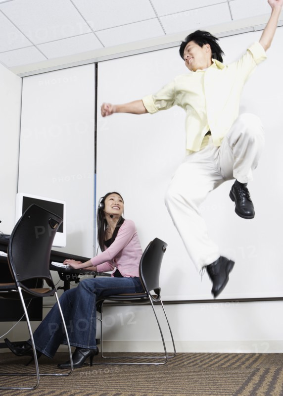 Asian man jumping next to Asian female computer service technician