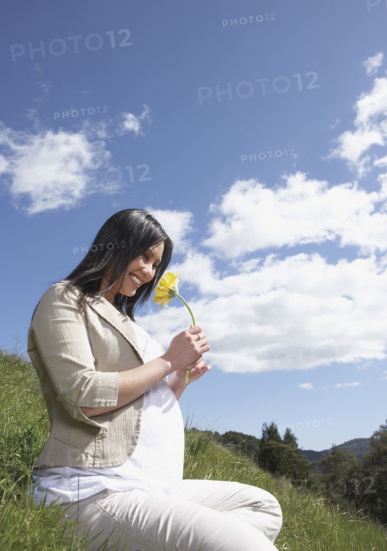 Pregnant Asian woman holding flower outdoors