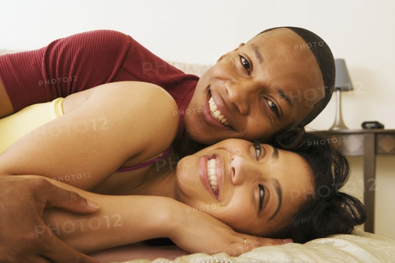 African couple hugging on bed