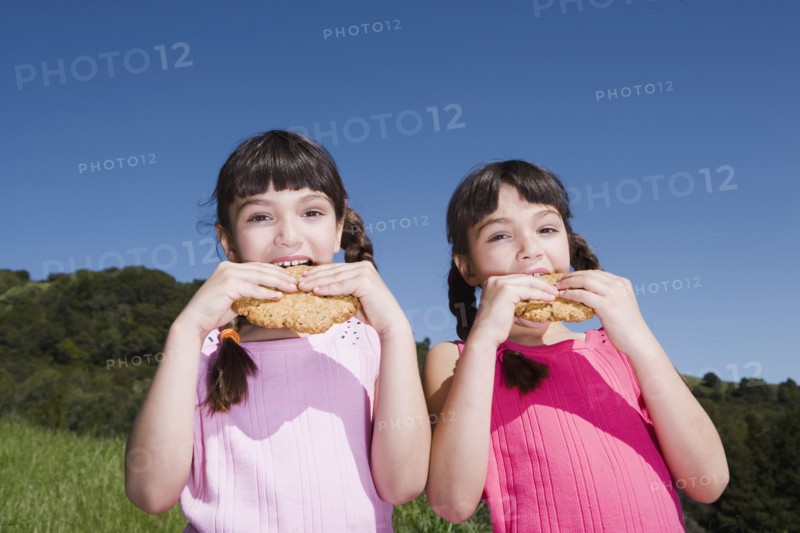 Young Hispanic sisters eating cookies outdoors