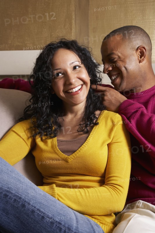 Multi-ethnic couple hugging on sofa