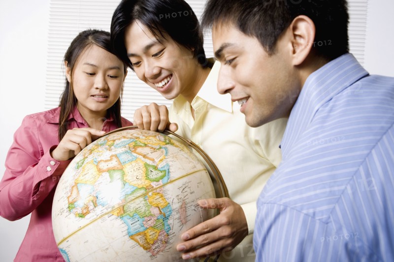 Three friends looking at globe