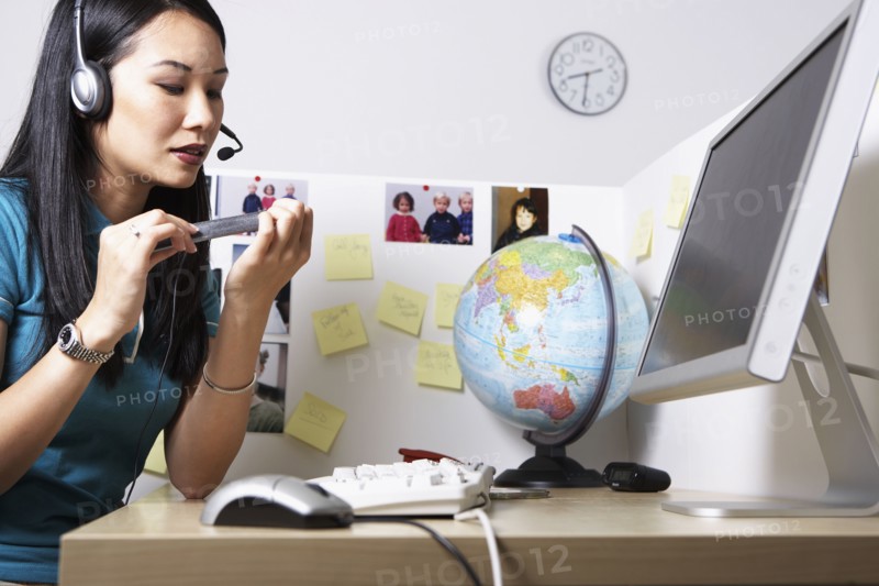 Asian businesswoman filing fingernails at desk