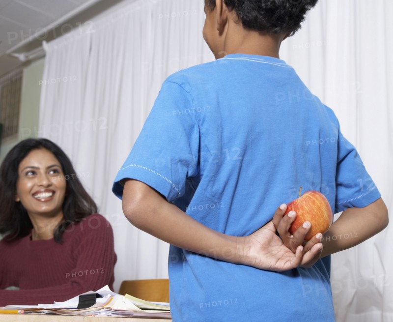Mixed Race boy giving apple to teacher