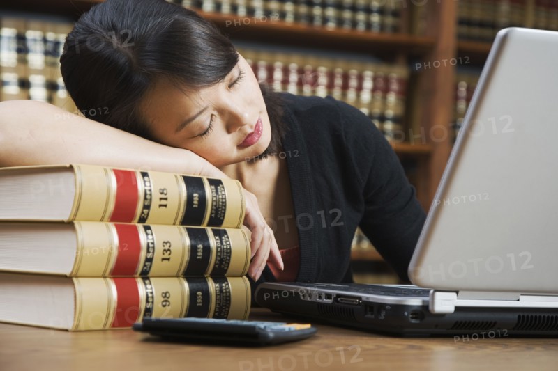 Asian woman sleeping on stack of library books