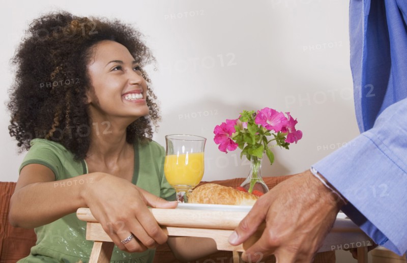 African man bringing breakfast in bed to wife