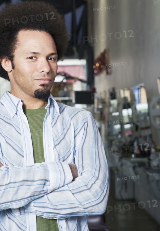 Mixed Race male hair stylist with arms crossed