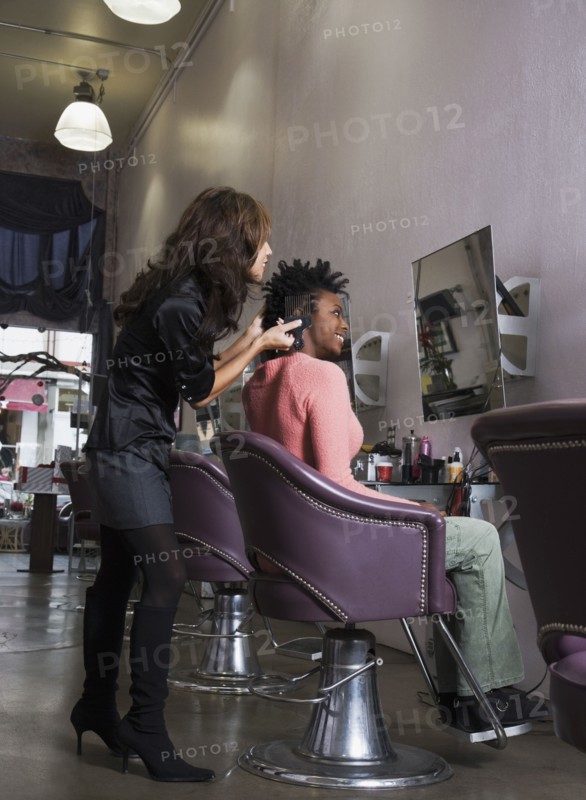 Hispanic hair stylist styling African woman's hair