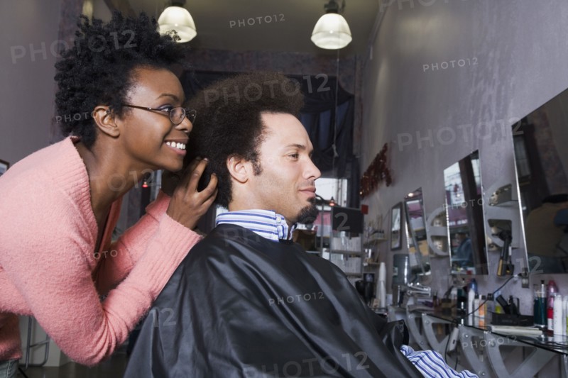 African hair stylist styling Mixed Race man's hair
