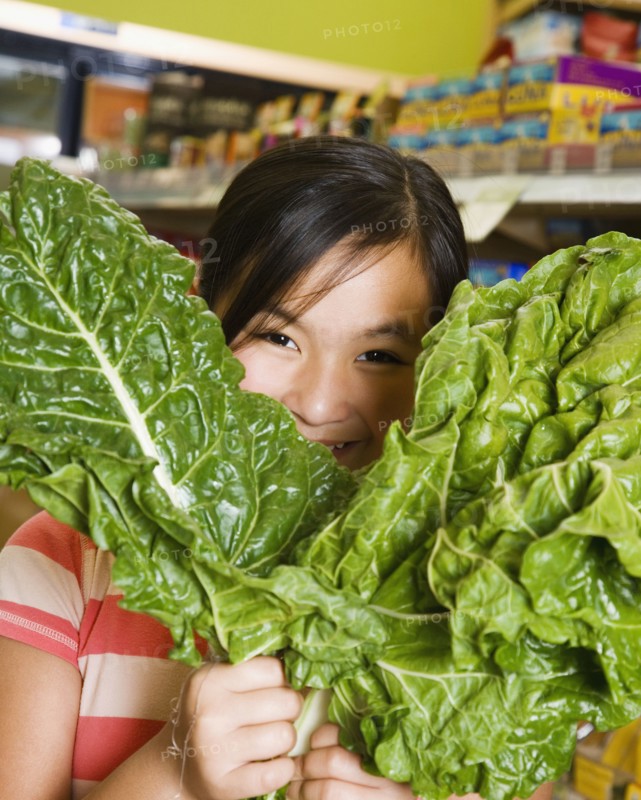 Asian girl holding green leaf vegetables
