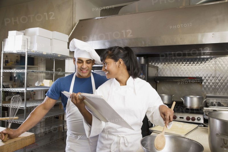 Multi-ethnic chefs looking at cookbook