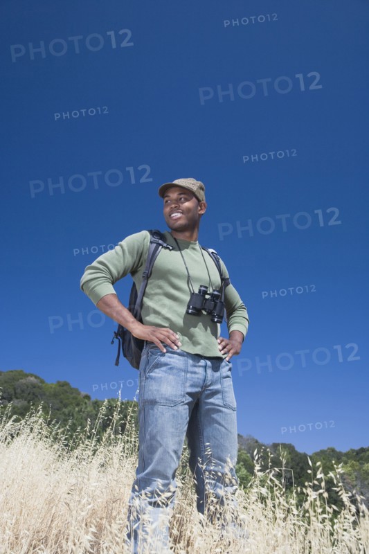 Mixed race man backpacking on hillside