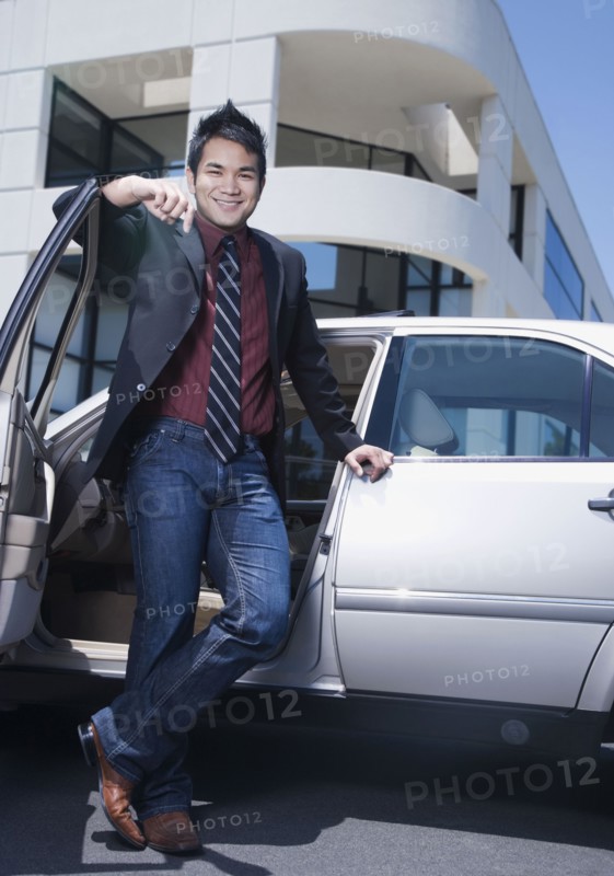 Asian businessman leaning on car