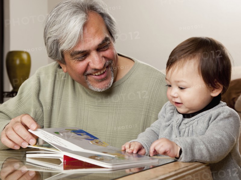 Grandfather reading book to granddaughter