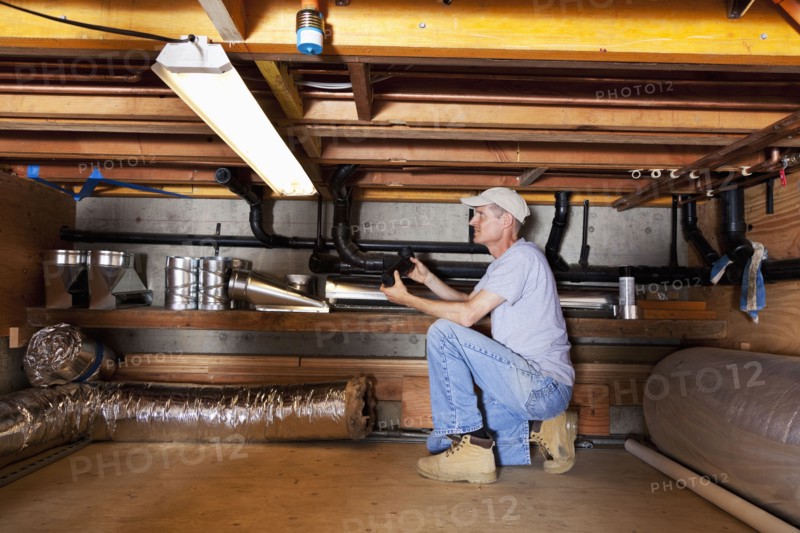 Caucasian plumber working on pipes