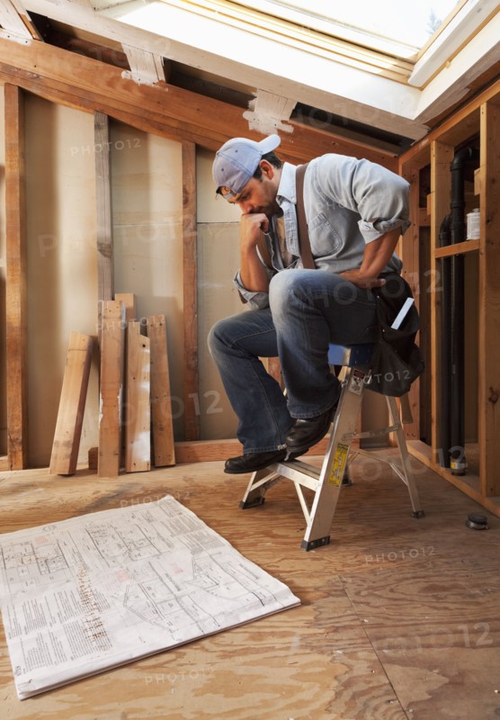 Hispanic construction worker looking at blueprints