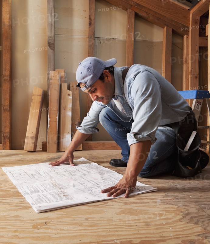 Hispanic construction worker looking at blueprints
