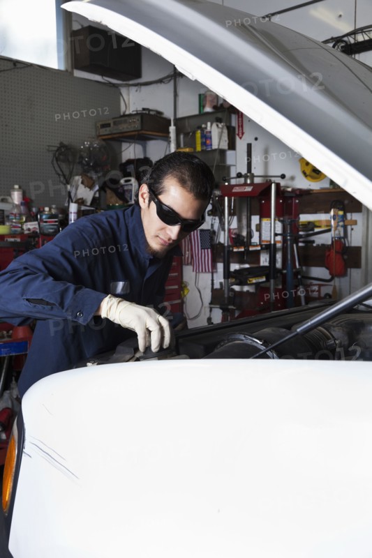 Hispanic mechanic working on car