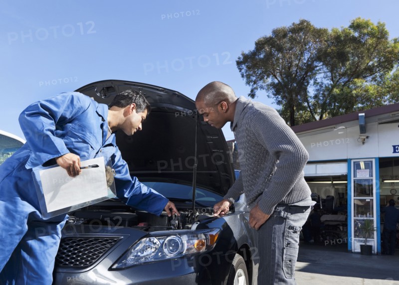Mechanic talking to customer about car engine