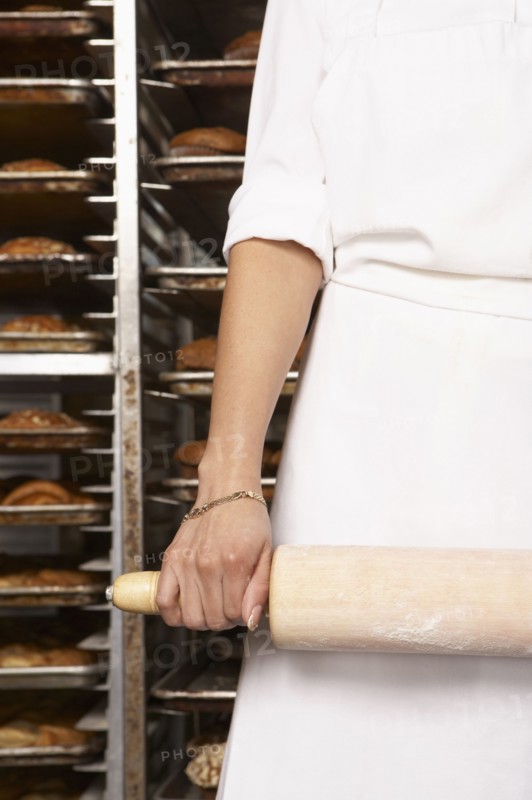 Hispanic baker holding rolling pin in bakery