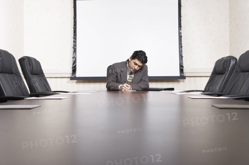 Mixed race businessman sitting at conference table