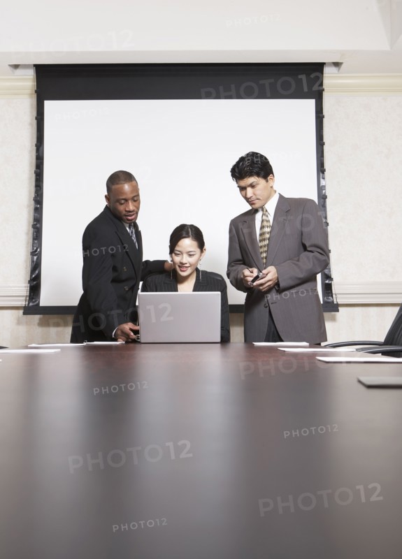 Business people using laptop at conference table