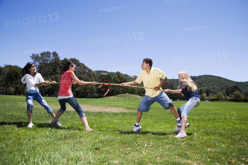 Children playing tug-of-war in field