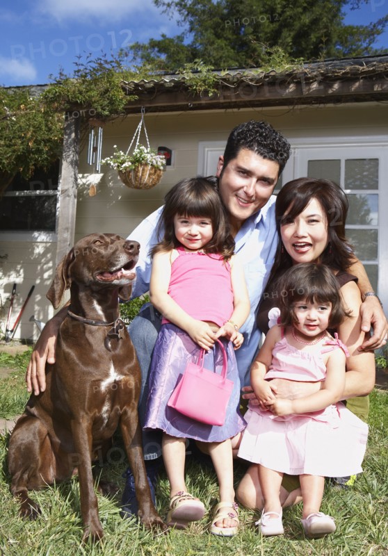 Family smiling together with dog in backyard