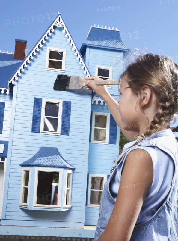 Mixed race girl painting doll house