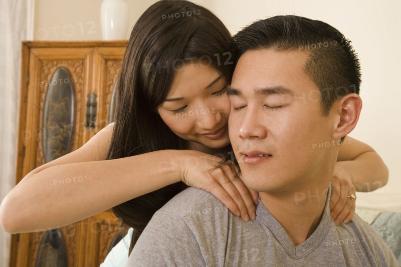 Chinese woman giving boyfriend shoulder massage