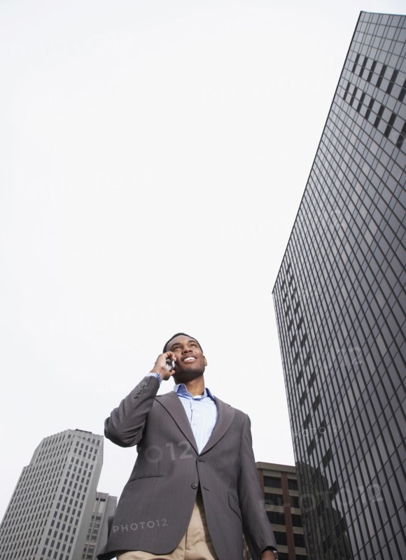 Mixed businessman talking on cell phone on city street