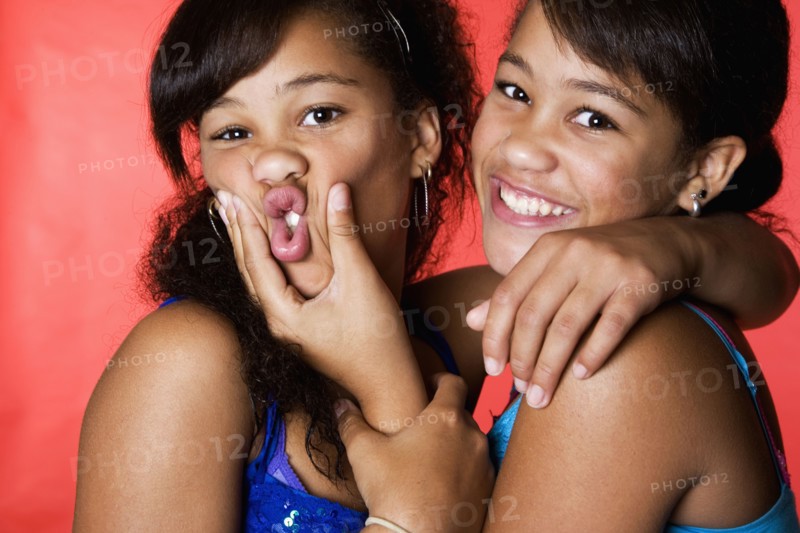 Mixed race teenage twin girls making faces
