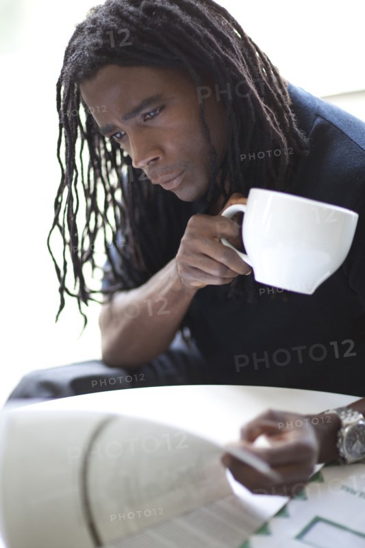 Mixed race businessman drinking coffee and reviewing report