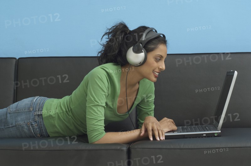Middle Eastern woman looking at laptop and wearing headphones