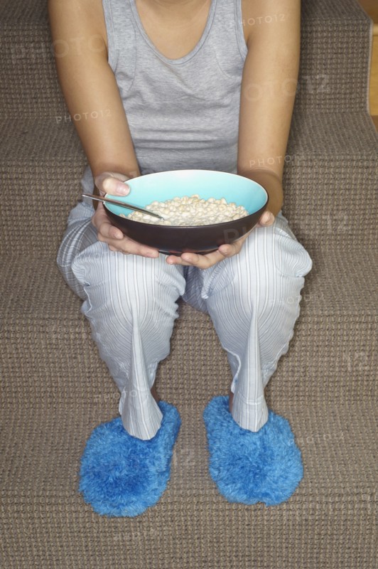Asian woman eating cereal on stairs