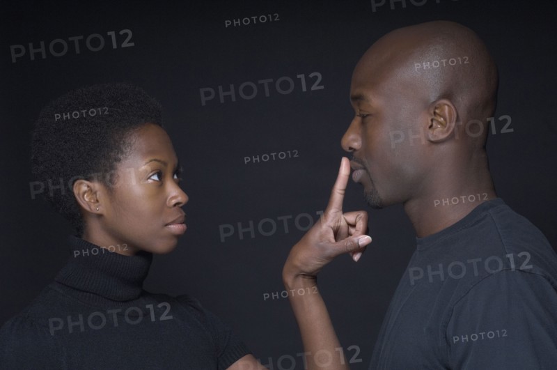 African woman putting finger on boyfriend's lips