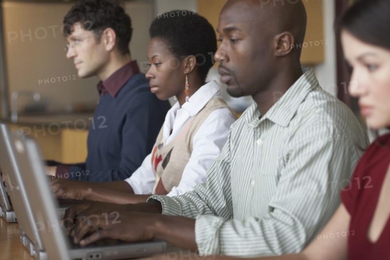 Multi-ethnic people typing on laptops