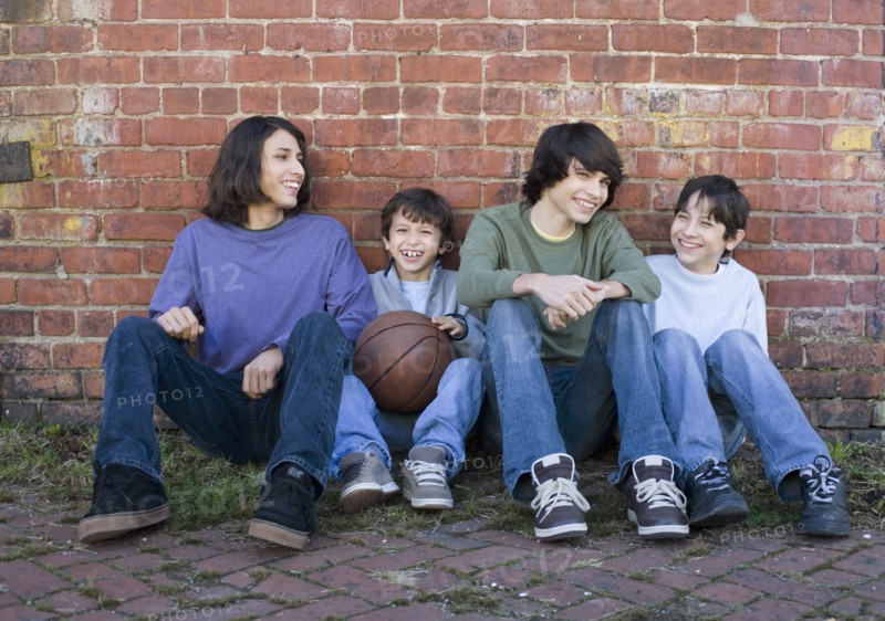 Hispanic brothers sitting with basketball
