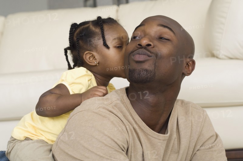 African girl kissing father's cheek