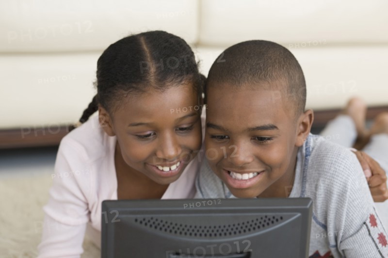 African brother and sister looking at laptop