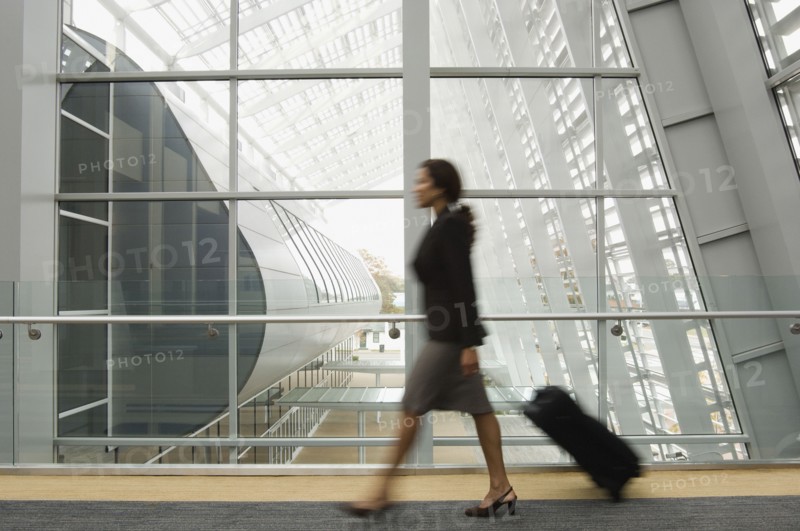 Hispanic businesswoman pulling suitcase