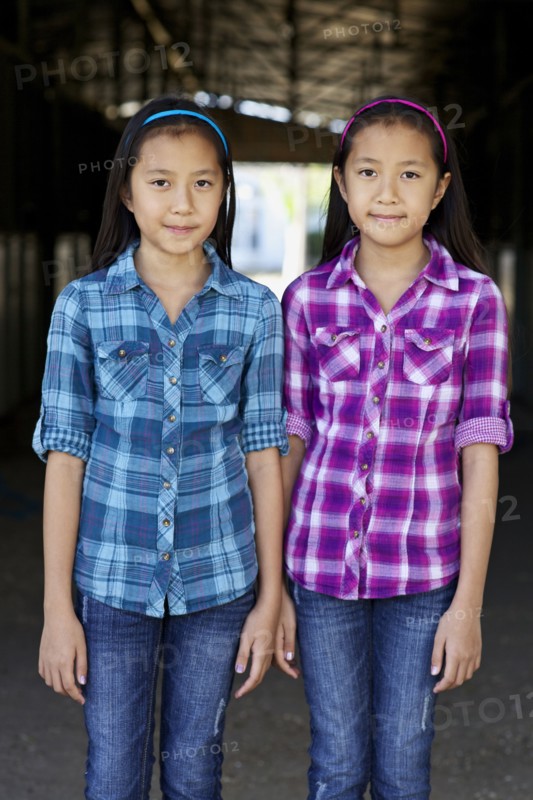Asian twin girls smiling in barn