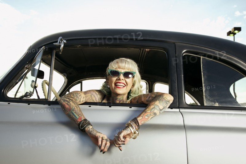 Woman with tattoos leaning out window of 1951 Chevy
