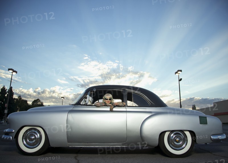 Woman with tattoos leaning out window of 1951 Chevy